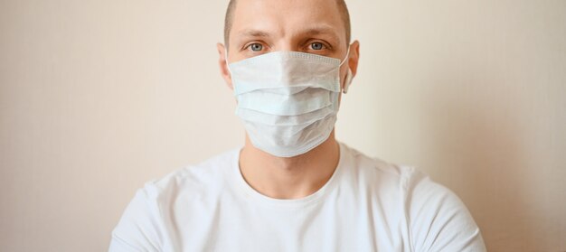 Chiuda sul ritratto di giovane medico europeo dell'uomo che indossa la prevenzione protettiva del virus della corona della maschera di protezione.