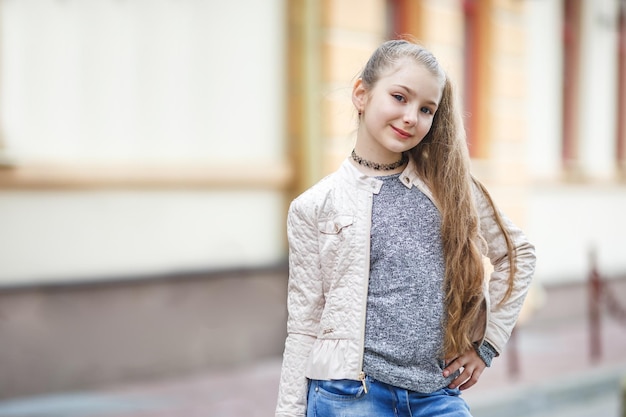 Chiuda sul ritratto di piccola bella ragazza alla moda del bambino sulla strada urbana