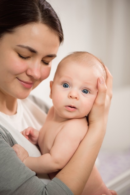 Chiuda sul ritratto di ragazza giovane e bella madre che bacia il suo bambino appena nato.