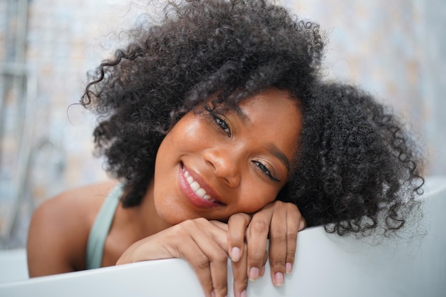 Chiuda sul ritratto di una ragazza afro allegra sorride con felicità al mattino