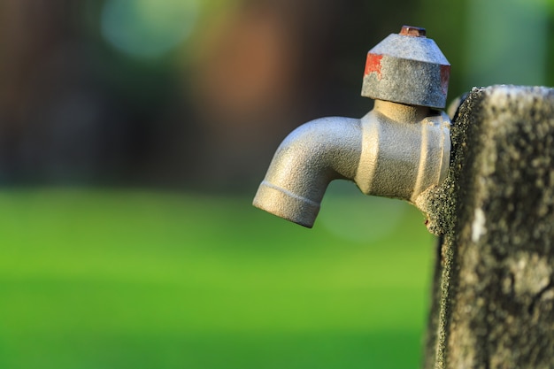 Chiuda sul vecchio rubinetto all&#39;aperto senza acqua in giardino sul fondo verde della sfuocatura