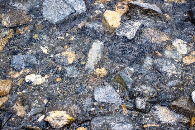 Chiuda sull'acqua calma chiara blu trasparente con la foto di concetto delle pietre