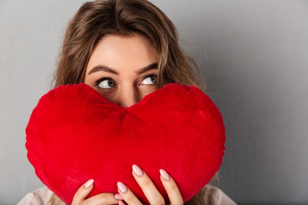 Chiuda sull'immagine della donna di mistero in maglietta che si nasconde dietro il cuore di gioia e distoglie lo sguardo sopra il gray