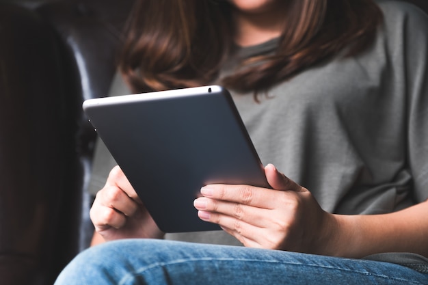 Chiuda sull'immagine di una tenuta della donna e di utilizzare il pc della compressa nel caffè moderno