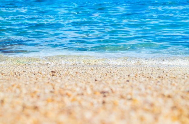 Chiuda sull'onda del mare blu sulla spiaggia della spiaggia di sabbia