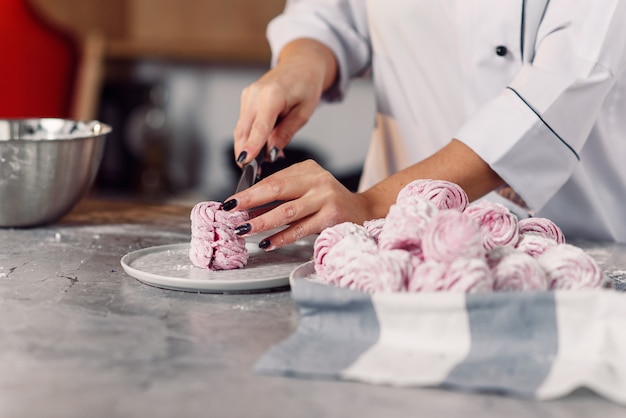 Chiuda sulla caramella gommosa e molle appena fatta del taglio manuale dello chef con un coltello. Verifica della qualità dei marshmallow fatti in casa.