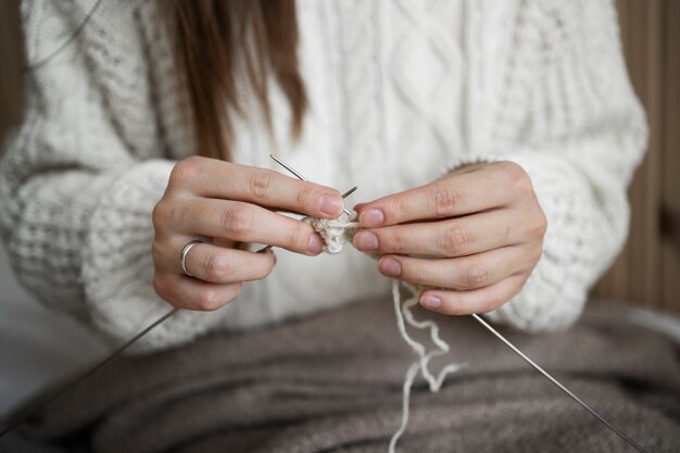 Chiuda sulla donna che lavora a maglia a casa