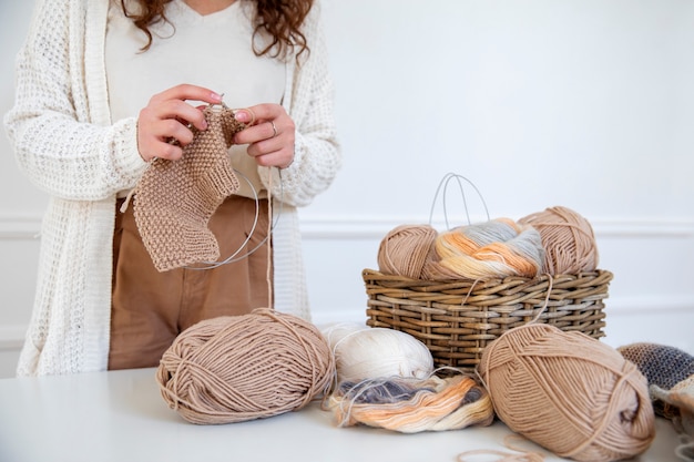 Chiuda sulla donna che lavora a maglia all'interno