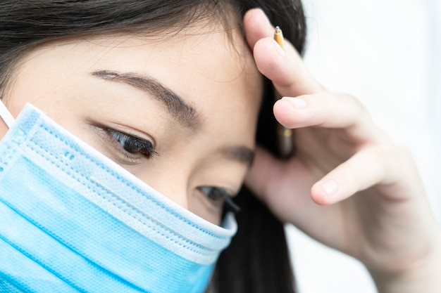 Chiuda sulla donna con la maschera da portare di emicrania per protezione