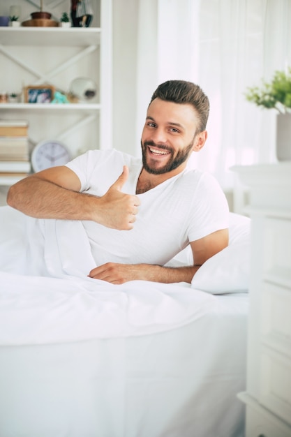 Chiuda sulla foto del bel giovane barbuto sdraiato a letto e rilassarsi la mattina