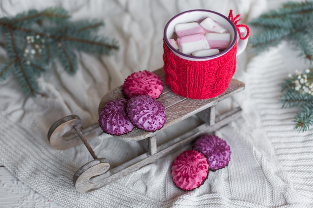 Chiuda sulla foto della tazza di Christmassy con le caramelle gommosa e molle vicino alle decorazioni