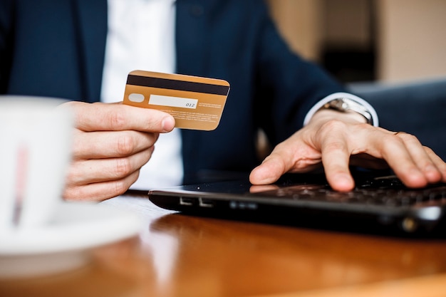 Chiuda sulla foto delle mani dell'uomo usando la carta di credito e l'acquisto di qualcosa in vendita.