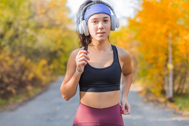 Chiuda sulla foto di un ritratto all'aperto di autunno della donna che corre