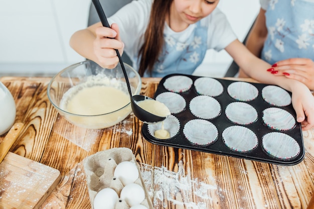 Chiuda sulla foto, figlia al processo di produzione dei biscotti alla cucina.