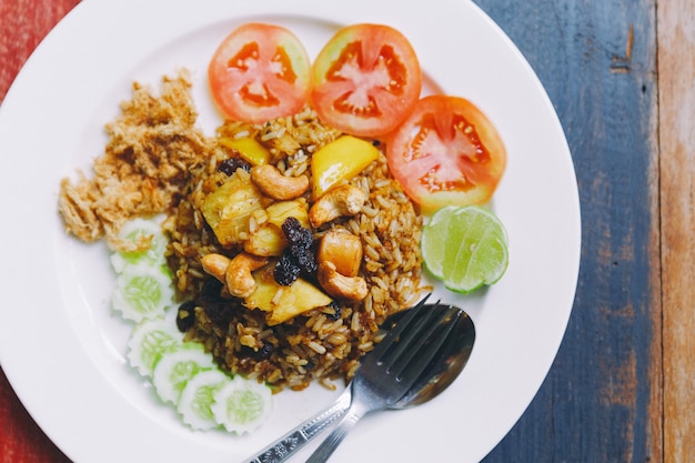 Chiuda sulla guarnizione tailandese del riso fritto dell&#39;ananas con l&#39;uva passa, gli anacardi e la carne di maiale tagliuzzata secca.