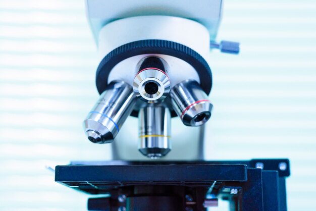 Chiuda sulla lente del microscopio per i batteri di diagnosi dello scienziato dal liquido del corpo Contro strumento medico