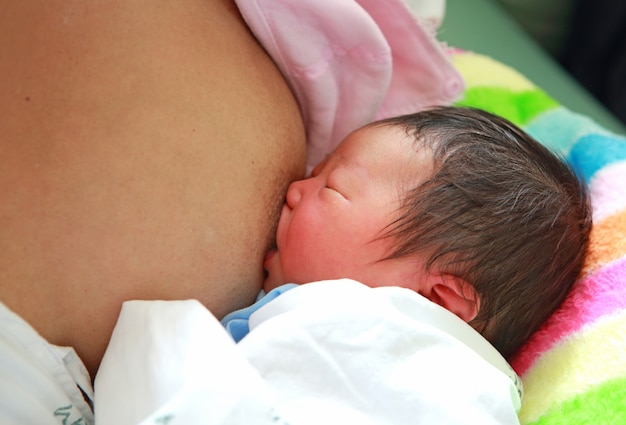 Chiuda sulla madre che allatta al seno il suo bambino appena nato.