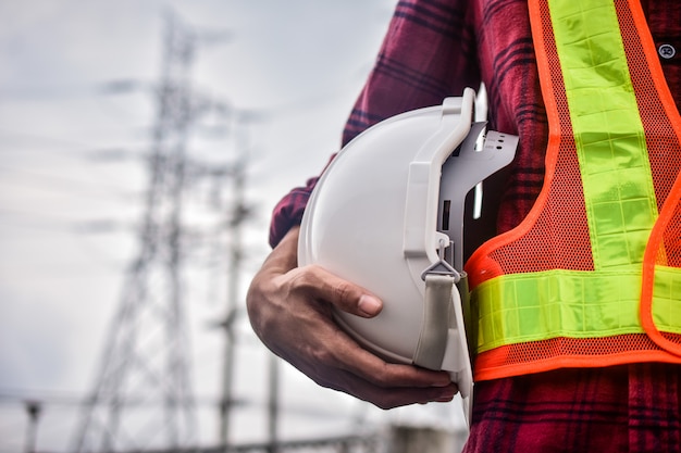 Chiuda sulla mano che tiene il concetto bianco di ingegneria del casco del casco