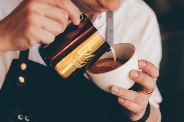 Chiuda sulla mano del barista che produce una tazza di caffè.