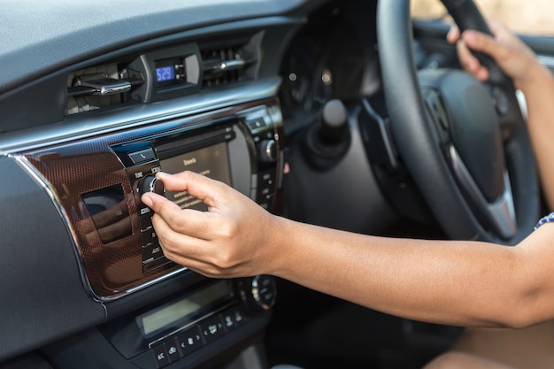 Chiuda sulla mano del driver regola il bottone audio nell&#39;automobile