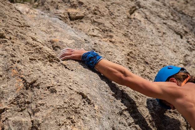 Chiuda sulla mano del giovane scalatore in una crepa mentre si arrampica su un muro in una giornata di sole