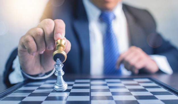 Chiuda sulla mano dell'uomo d'affari che gioca gli scacchi e vinca nel concetto di affari di gioco da tavolo, di strategia e di pianificazione