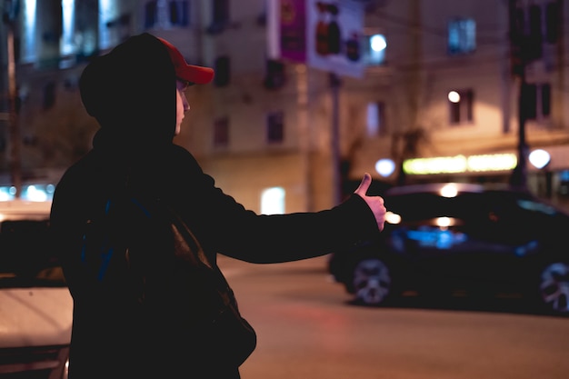 Chiuda sulla mano della persona che fa auto-stop e che aspetta un&#39;automobile sta su un&#39;autostrada nella notte