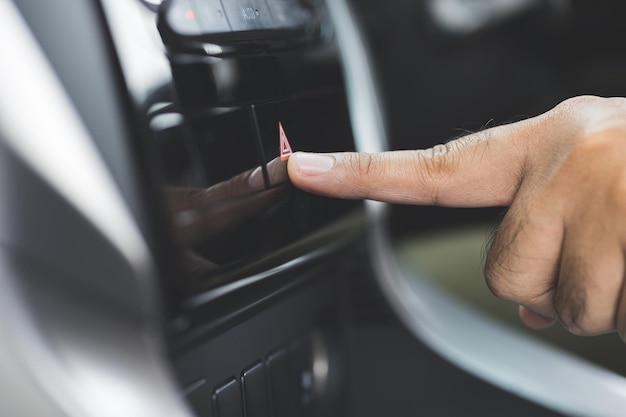 Chiuda sulla mano maschio che preme il pulsante di emergenza in auto, fermata sul ciglio della strada, incidente d'auto.