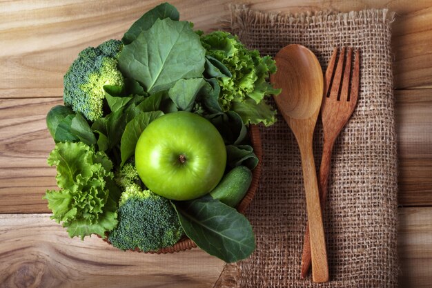 Chiuda sulla mela verde con verdura verde mista