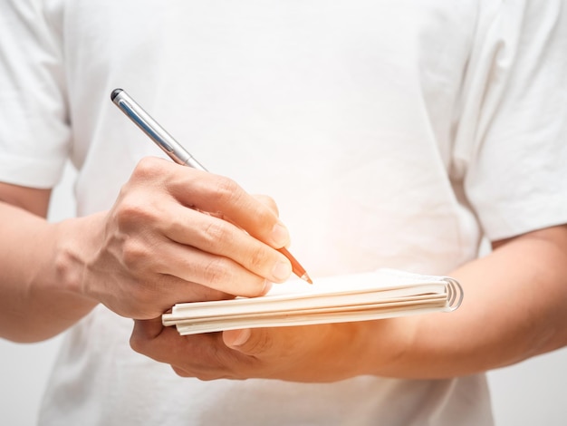 Chiuda sulla penna di scrittura della mano dell'uomo sul libro del diario