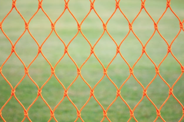 Chiuda sulla rete di calcio arancio sul fondo dell&#39;erba verde