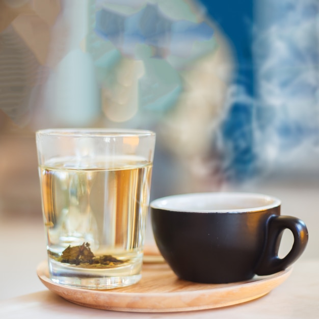 Chiuda sulla tazza di caffè con vapore sulla tavola in caffè