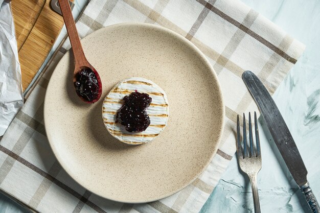 Chiuda sulla testa grigliata del formaggio del camembert di vista sul piatto e sul tagliere con inceppamento. tavolo trama leggera.