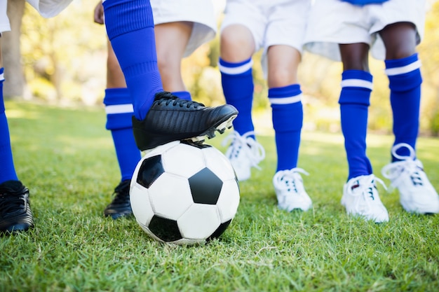 Chiuda sulla vista del pallone sotto le scarpe da calcio con il gioco dei bambini