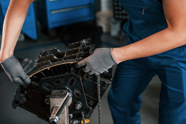 Chiuda sulla vista del riparatore professionista in garage che funziona con il motore di automobile rotto