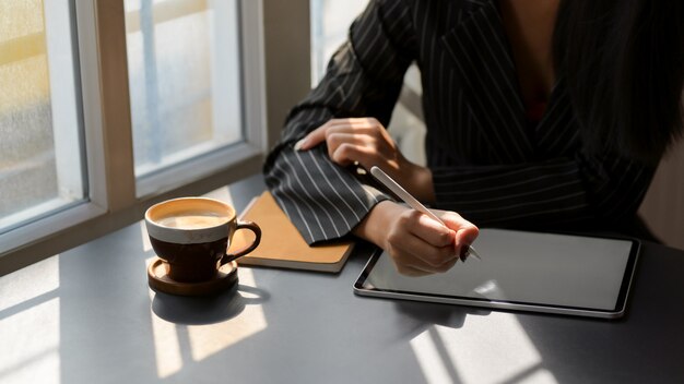 Chiuda sulla vista delle free lance femminili che lavorano alla compressa digitale in caffetteria