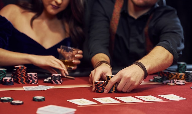 Chiuda sulla vista delle mani eleganti dei giovani che giocano a poker nel casinò