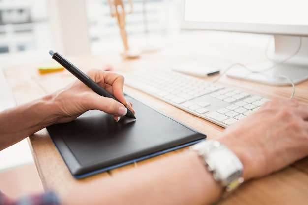 Chiuda sulla vista delle mani facendo uso di digitalizzatore e del computer