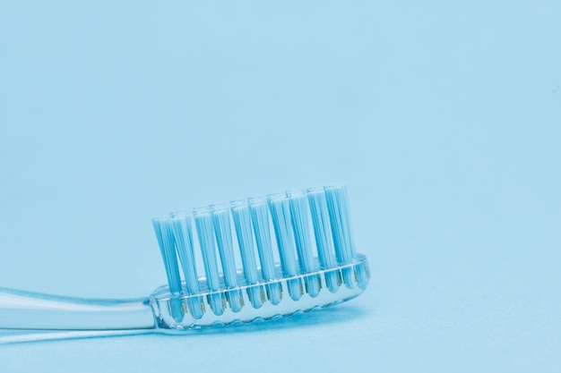 Chiuda sulla vista dello spazzolino da denti trasparente su fondo blu.