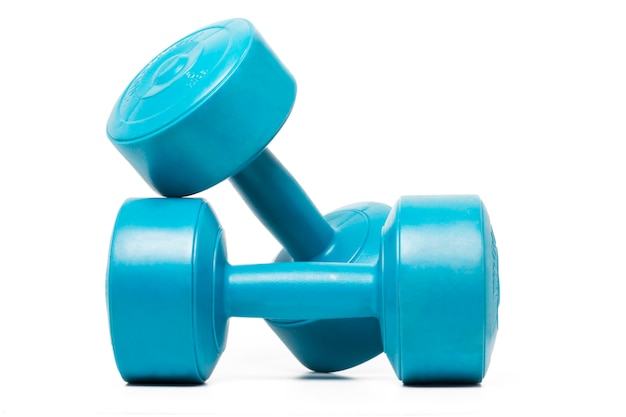 Chiuda sulla vista di un accoppiamento dei dumbbells di forma fisica isolati su una priorità bassa bianca.