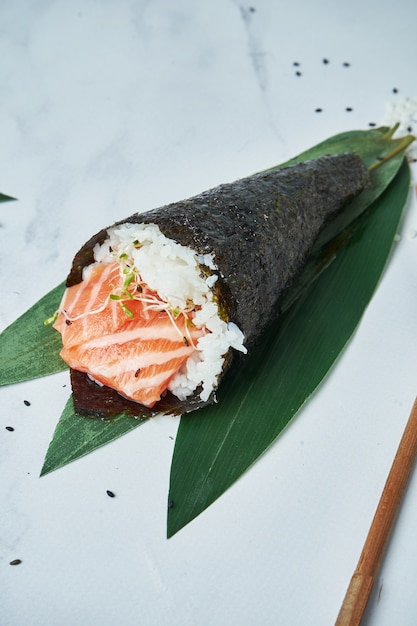 Chiuda sulla vista sui sushi freschi e di temaki dei frutti di mare con i salmoni su bianco.