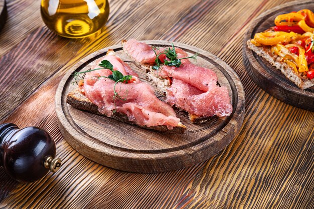 Chiuda sulla vista sulla Bruschetta con il tonno sul bordo di legno. Bruschetta italiana fresca sulla tavola di legno con lo spazio della copia per testo o progettazione. Immagine per menu o ricetta. Spuntino di pesce fresco