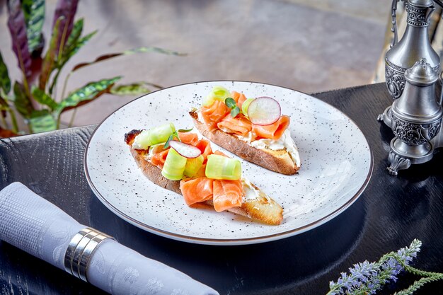 Chiuda sulla vista sulla ciabatta con salmone e crema di formaggio servito sul piatto bianco. Cibo del ristorante. Pranzo a base di pesce. Cucina italiana. Panino con frutti di mare. Cibo sano e dietetico