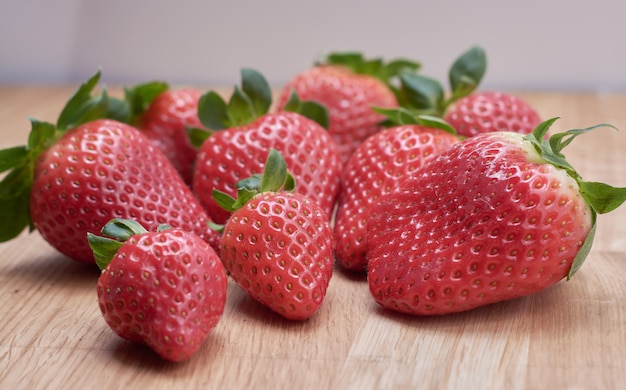 Chiuda sulle fragole fresche con fondo di legno naturale