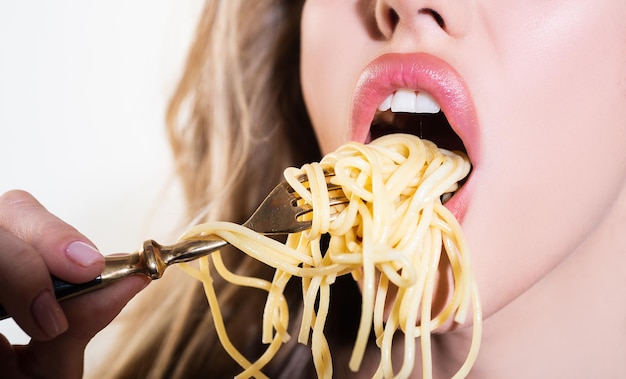 Chiuda sulle labbra sexy con la pasta delle tagliatelle. La bocca femminile mangia gli spaghetti.