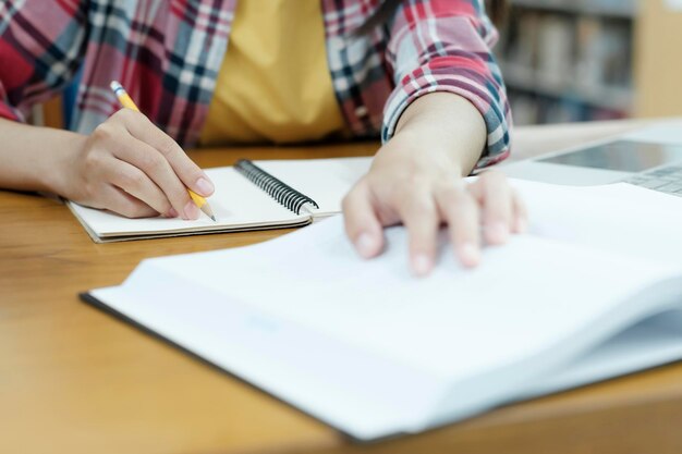 Chiuda sulle mani con scrittura a penna sul taccuino