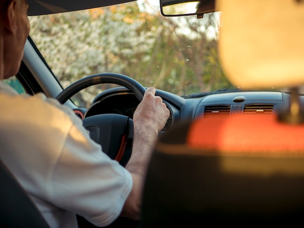 Chiuda sulle mani dell'uomo su un timone dell'automobile mentre lo guida