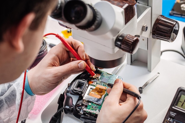 Chiuda sulle mani di un lavoratore di servizio che ripara la macchina fotografica digitale