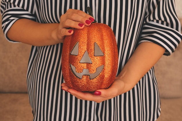 Chiuda sulle mani femminili che tengono la zucca di Halloween