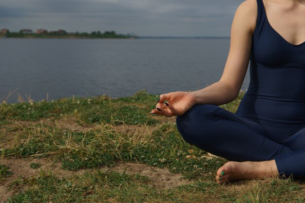 Chiuda sulle mani la donna fa yoga all'aperto concetto yoga